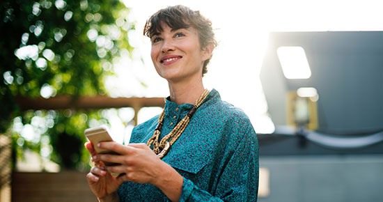 Lady outdoors smiling as she accesses her mobile ready CCH Site Builder website